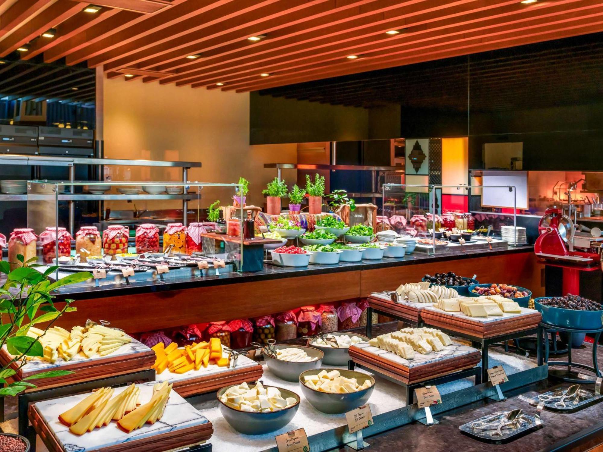Swissotel The Bosphorus Istanbul Eksteriør billede The photo showcases a buffet display featuring a variety of foods. There are several types of cheese and fruits laid out on tables, along with jars possibly containing preserves or spreads. Fresh greenery and herbs are also visible, enhancing the aes